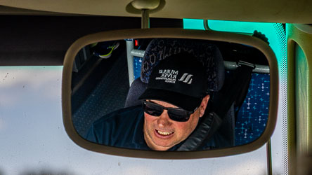 Reflection in a rear vision mirror of Ross, the bus driver.