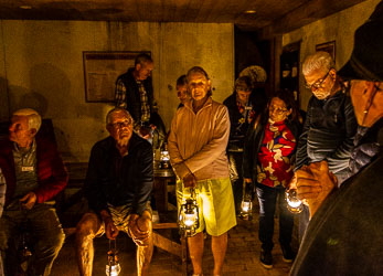 Group of visitors holding lanterns inside The Shades, the underground bar beneath the Star Hotel at Echuca, with warm yellow light illuminating rustic walls and wooden ceiling.