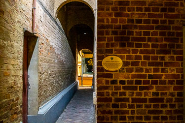 Narrow brick alleyway with arched ceiling and heritage plaque leading toward the Port of Echuca, barely lit at night.