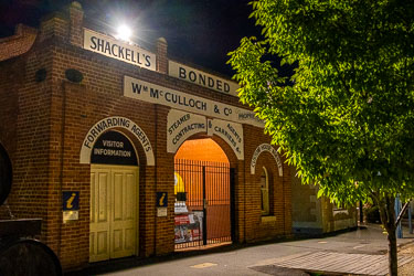 Historic brick building at night in Echuca with arched doorways and vintage signage reading "Shackell