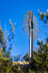 Large steel sculpture looking rather like a toilet brush, standing vertically and before a clear blue sky. [4409]