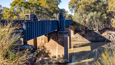 Bridge structure crossing the river with trees nearby.