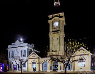 Historic building with clock tower lit at night.