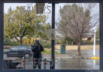 Reflection of person taking photo in shop window with lettering "Fahey