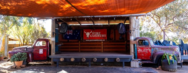 Outdoor stage with canopy, red vintage trucks, chairs, and banner reading "Spirit of Country."