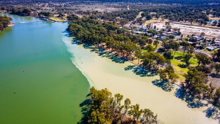 Aerial view showing two rivers meeting near a weir with town buildings along the bank.