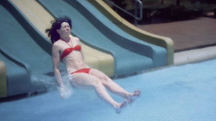 Young lady in red bikini grimaces as she reaches the bottom of a water slide.