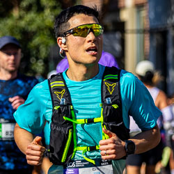 A runner at the 32 km mark keeps his rhythm steady through Taylor Square, eyes forward and mind fixed on the finish. His gear and focus reflect the discipline of long‑distance running. [3975]