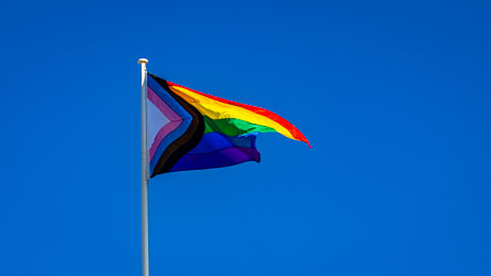The Progress Pride Flag flies high over the Courthouse Hotel at Taylor Square, its colours vivid against a perfect Sydney winter sky — a symbol of inclusion and local spirit. [3907]
