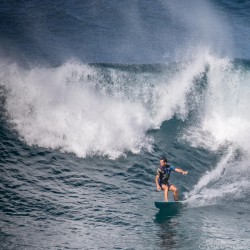 A surfer carving across the face of a massive four-meter wave with a huge crest of white water collapsing behind him at Bronte Beach.