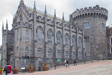 Dublin Castle in Ireland showing medieval round tower and Gothic‑style hall with arched windows and people walking nearby.