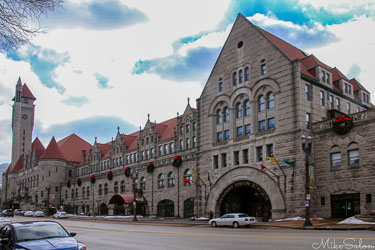 Historic Union Station in St Louis, Missouri, with stone façade, arched entrance, red‑tiled roof, and clock tower under partly cloudy sky.
