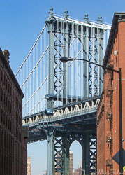 View of Manhattan Bridge framed by red‑brick buildings in Brooklyn