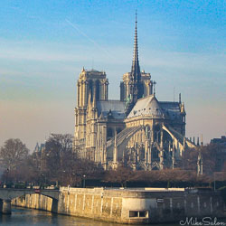 Notre Dame Cathedral in Paris before the 2019 fire, viewed from across the Seine with spire and twin towers under clear winter sunlight.