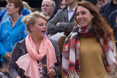 Two women smiling and chatting while listening to street musicians in Dublin, surrounded by a lively crowd.