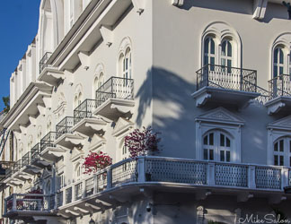 Restored colonial building in Casco Viejo, Panama City, with light‑coloured walls, arched windows, and balconies decorated with red flowers under morning sunlight.